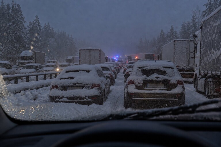 Helt stopp på motorvägen i snöoväder, översnöade bilar i båda riktningar och blåljus långt fram